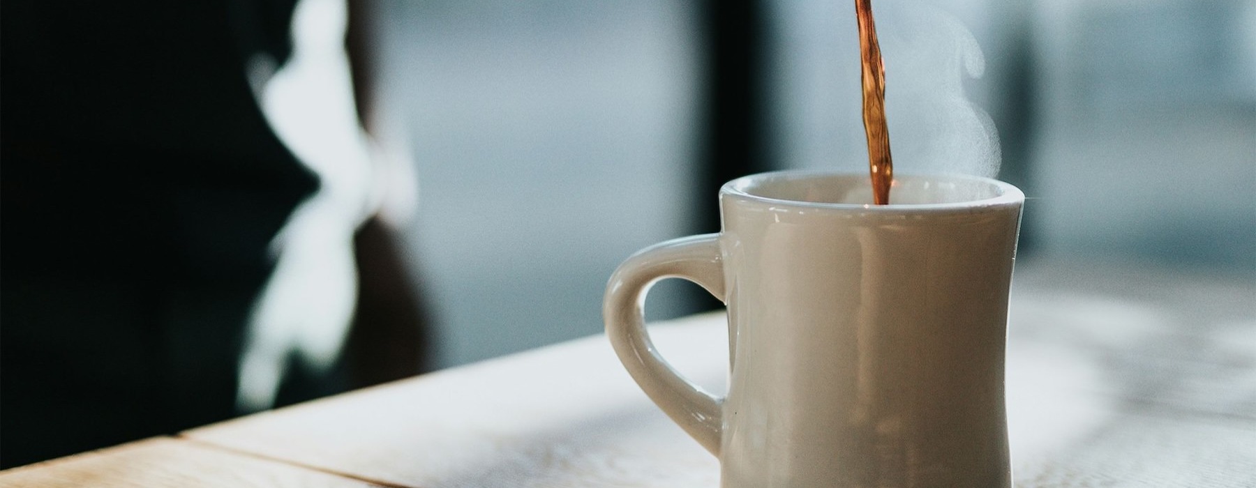 a person pouring a carafe of coffee into a cup